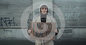 Female millennial supporting human rights and no racism campaign. Student girl holding placard against racism while