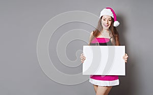female miss santa in pink christmas costume holding blank sign