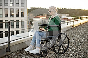 Female with mobility impairment using computer in open air
