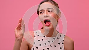 Female mocks showing hand blah blah blah gesture on a pink background.