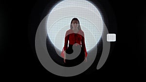 Female model against digital wall. Woman in red dress walking on runaway catwalk fashion show in front of digital screen