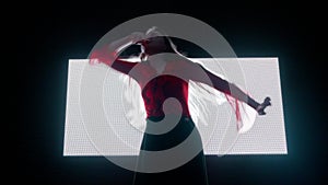 Female model against digital wall. Woman silhouette dancing in front of digital screen wall with strobing symbols