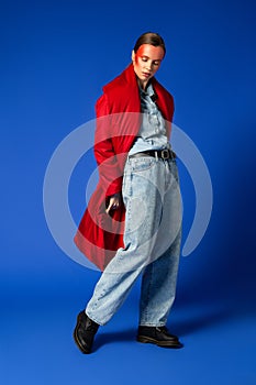 Female model in baggy coat walking against blue background