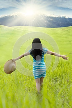 Female model with hat walks on meadow