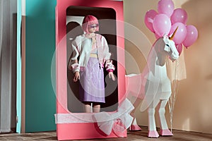 female model in pink wig standing in decorative box