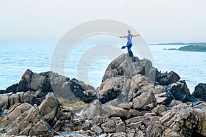 Female model posing on a beach with rocks