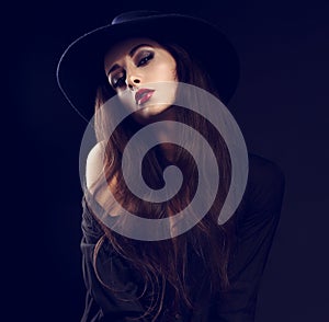 female model posing in black shirt and elegant hat with red