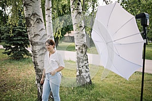 Female model posing next to birch tree and umbrella on stand