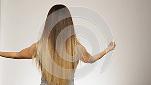 Female model shows her long healthy blonde hair back view slow motion