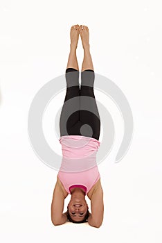 Female model in sirsasana yoga pose balancing vert