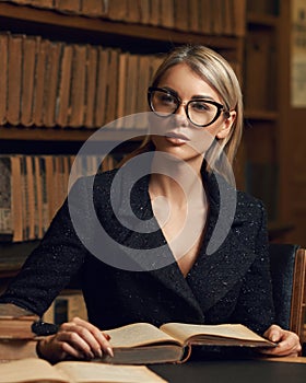 Female model sitting at desk and reading book at library