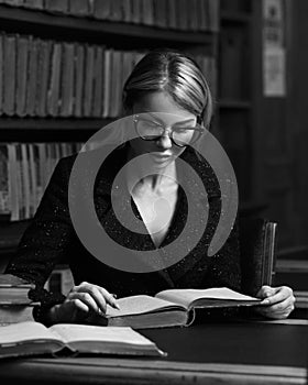 Female model sitting at desk and reading book at library