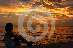 A female model sitting on a pier at sunset at Ba Keo Beach, Phu Quoc Island