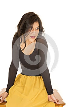 Female model sitting wearing black top and yellow skirt