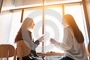 Female models sit and talk in cafe. Young women having coffee during lunch