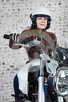 Female motorcyclist in open helmet holds steering wheel while sitting on the motorbike