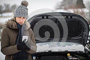 Female Motorist Broken Down In Snow Calling For Roadside Assistance On Mobile Phone