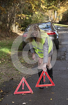 Female motorist placing red warning triangles in the road,