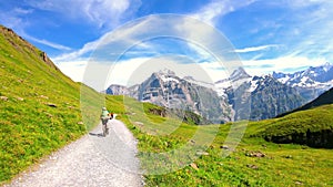 Female mountain biker riding in the Swiss Alps by Grindelwald. Famous mountains Jungfrau, Eiger and Monch in the background