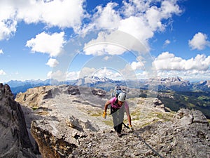 Female mountain climber reaches the summit with great Dolomites landscape behind