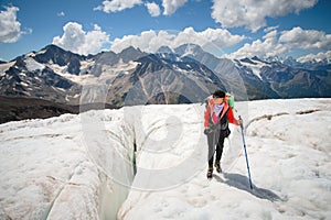 Female mountaineer enjoying the beauty of the glacier walks on the glacier in the crampon and sunglasses. Against the