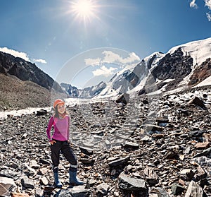 Female mountaineer in a helmet near the top of the mountain pass in the middle of rocks and glaciers