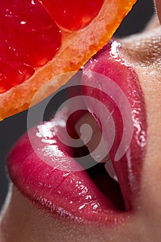 Female mouth with pummelo slice photo