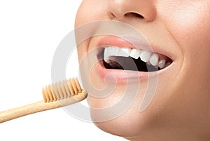 Female mouth with white teeth and bamboo toothbrush