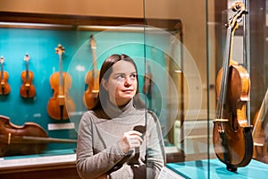 Female museum visitor examining ancient musical instruments