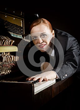 Female musician dressed in a man`s suit lies on a piano keyboard photo