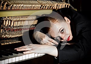 Female musician dressed in a man`s suit lies on a piano keyboard photo