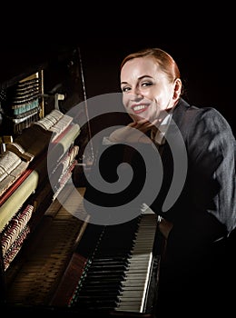 Female musician dressed in a man`s suit sitting next to the piano photo