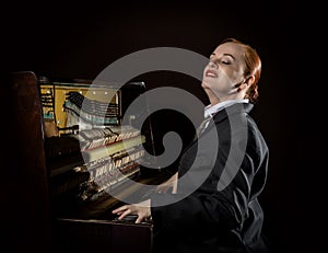 Female musician dressed in a man`s suit sitting next to the piano photo