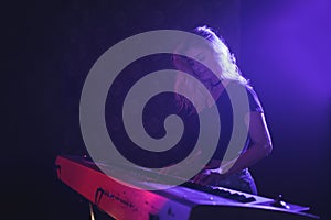 Female musician playing piano on stage in nightclub