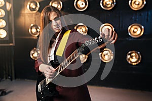 Female musician in suit playing on electric guitar