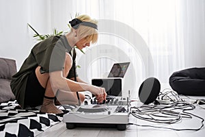 Female musician wearing headphones using dj console