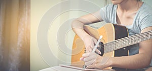 Female musicians play guitar and write songs using the tablet.This image is blurred and soft focus.