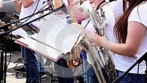 Female musicians play saxophones in municipal orchestra performing at concert open air.