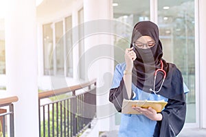 Female Muslim doctor in Abaya niqab traditional clothes works at modern clinic office checking photo