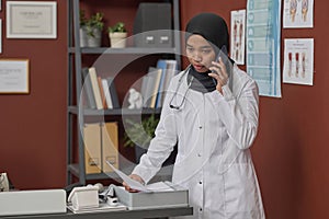 Female Muslim Doctor Having Conversation Over Mobile Phone at Workplace