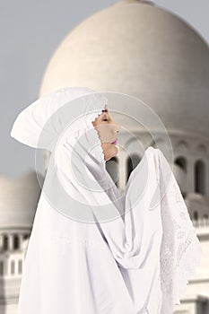 Female muslim in white praying at mosque