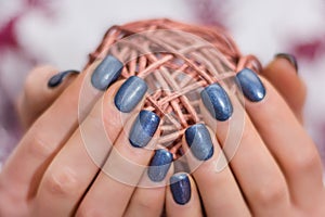 Female with navy blue nails polish holding decorative hank