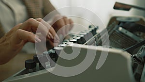 Female neat manicured well-groomed hands typing on vintage typewriter at daytime