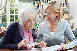 Female Neighbor Helping Senior Woman With Domestic Finances