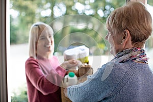 Female Neighbor Helping Senior Woman With Shopping photo