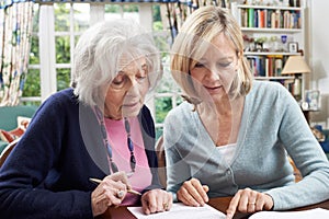 Female Neighbor Helping Senior Woman To Complete Form