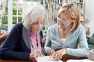 Female Neighbor Helping Senior Woman To Complete Form