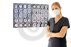 Female neurologist specialist professional doctor with mask reviewing brain scans