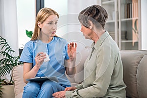 Female nurse in blue uniform explain dosage of antibiotic pill to woman