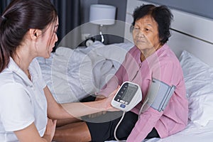 Female nurse checking blood pressure of a senior woman